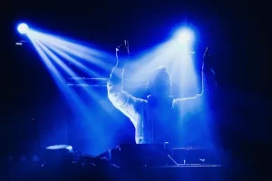 DJ Diego Sánchez en cabina durante boda en Colombia, con audífonos y brazos en alto bajo iluminación azul profesional