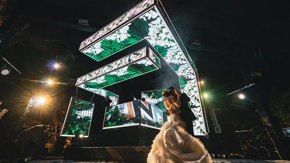 Bride and groom sharing their first dance on a custom 3D LED DJ stage in Colombia, as the groom embraces the bride and gently leans her back